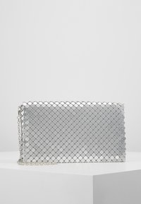 Silberne metallische Clutch mit hexagonalem Muster, ausgestattet mit einer Kettenriemen und einer glänzenden Oberfläche. Rechteckige Form mit einem Reißverschluss.