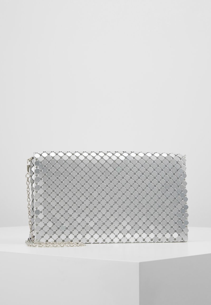 Silberne metallische Clutch mit hexagonalem Muster, ausgestattet mit einer Kettenriemen und einer glänzenden Oberfläche. Rechteckige Form mit einem Reißverschluss.
