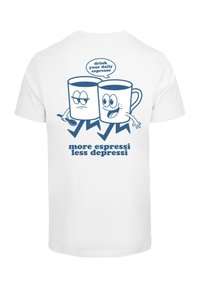 White t-shirt featuring blue cartoon coffee cups with expressive faces, holding a spoon, and text—"drink your daily espresso" and "more espressi less depressi."