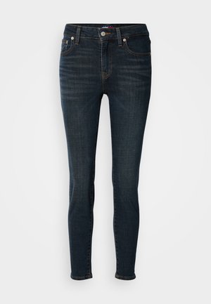 Jeans in denim blu scuro con vestibilità slim. Le caratteristiche includono cinque tasche, chiusura con bottone e dettagli di cucitura sottili. Tessuto liscio, gamba affusolata.