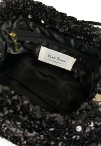 Svart paljettclutch med en slät textur inuti, dragkedjestängning och en etikett med texten "Part Two" sydd inuti.