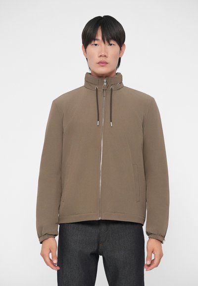 Giacca marrone con zip e colletto alto, dotata di cordini, due tasche laterali e polsini a costine, realizzata in un tessuto liscio.