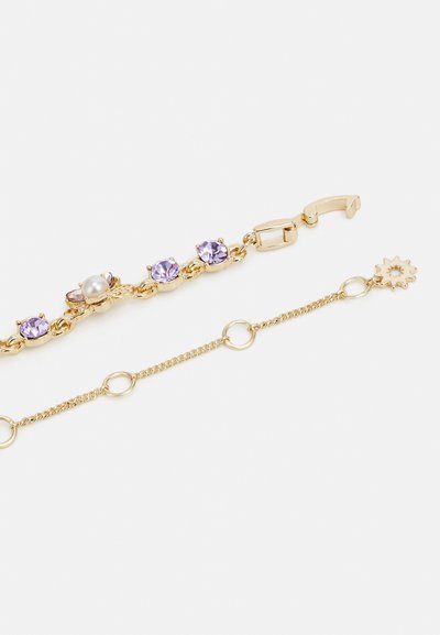 Guldtonet armbånd med vekslende lavendelkrystaller, en perle, og en delikat kæde med cirkulære led og en solformet accent.