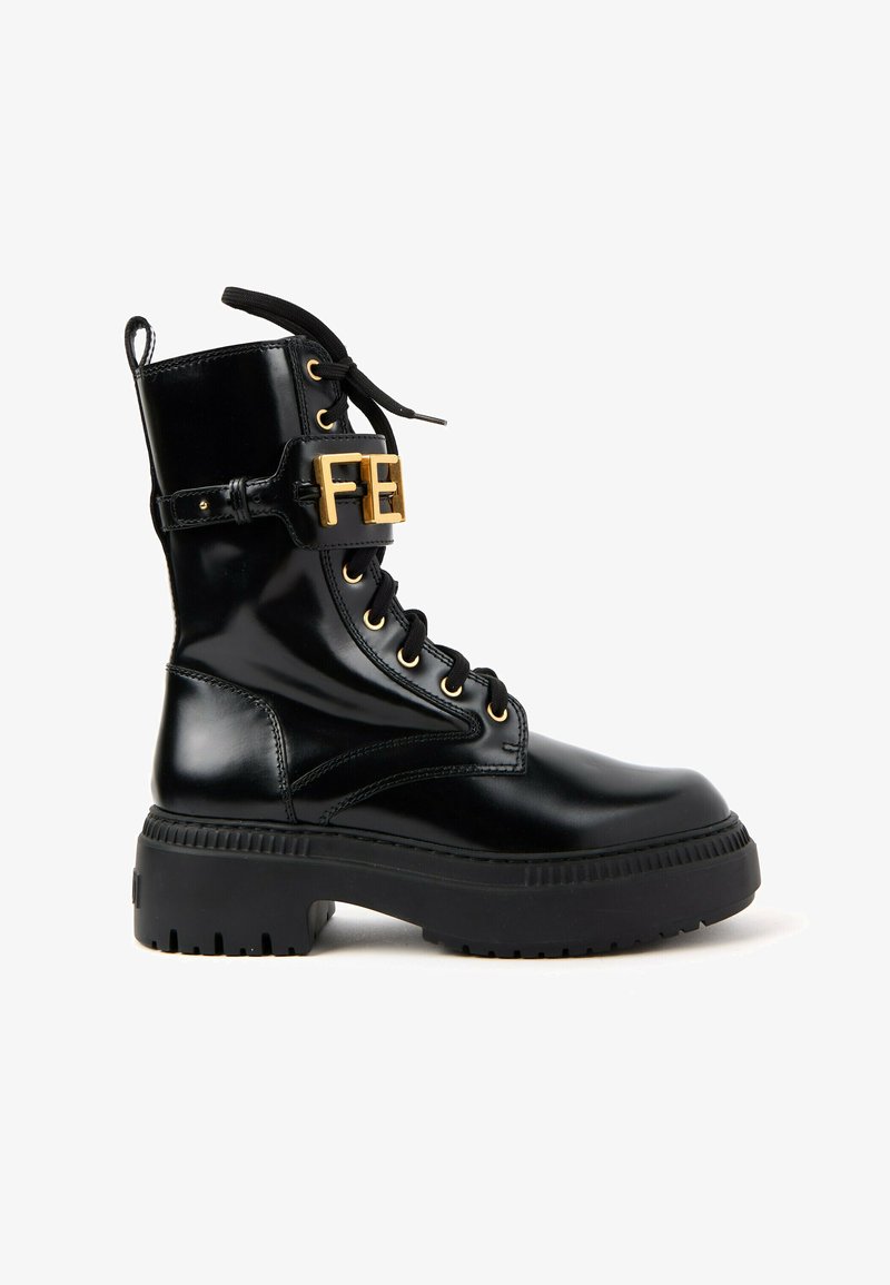 Botte de combat noire brillante avec semelle épaisse, fermeture à lacets à l'avant et détail de boucle dorée avec les lettres FE sur la sangle de la cheville.