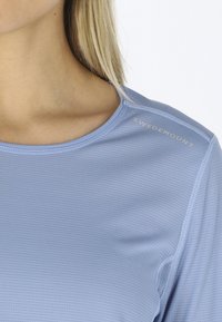 Lyseblå atletisk top lavet af strikket stof med ribbet mønster. Har rund halsudskæring og "SWEDEMOUNT" logo på skulderen.