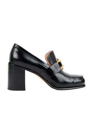 Mocassin femme en cuir noir avec un talon bloc et une boucle décorative dorée sur la partie supérieure, vu de côté.