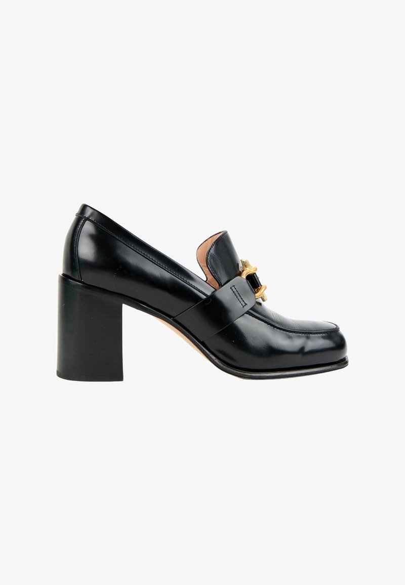 Mocassin femme en cuir noir avec un talon bloc et une boucle décorative dorée sur la partie supérieure, vu de côté.