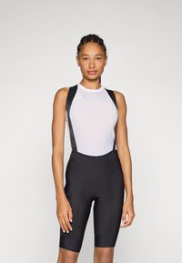 Sorte sykkelshorts med en teksturert, pustende hvit mesh-overdel. Justerbare stropper og en tettsittende design. Forsterket polstring i seteområdet.