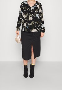 Czarna bluzka w kwiaty z długimi rękawami, dekoltem V, połączona z czarną, prążkowaną spódnicą midi z bocznym rozcięciem i marszczeniami. Czarne botki za kostkę z żółtymi akcentami.