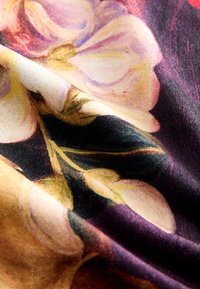 Stoff mit einem Blumenmuster aus rosa und gelben Blumen auf dunklem Hintergrund, der eine glatte Textur und lebendige Farben zeigt.