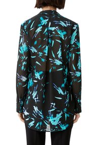 Blouse transparente noire à manches longues, présentant un motif abstrait multicolore en turquoise et bleu, avec des poignets boutonnés et un ourlet incurvé.