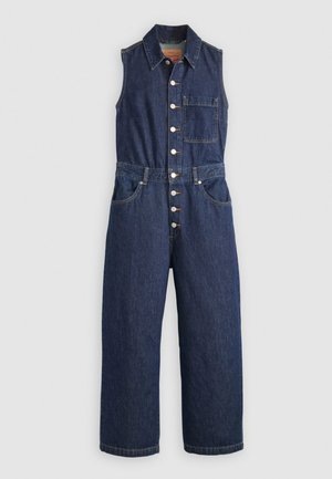 Utility jumpsuit in denim, senza maniche, di colore blu scuro, con bottoni frontali, colletto e tasca sul petto. Vestibilità ampia con dettagli di cucitura in evidenza.