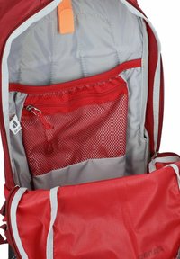 Intérieur d'un sac à dos rouge montrant un doublure grise rembourrée, une poche en maille zippée et un grand compartiment avec des accents gris et rouges.