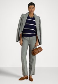 Sivý károvaný oblek s priliehavým blejzrom a strihanými nohavicami. Pod tým modrý pruhovaný sveter, doplnený hnedou kabelkou a hnedými mokasínami.