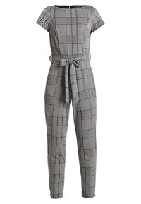 Kostičkovaný overal v černobílých tónech, má krátké rukávy, opasek v pase a zúžené nohavice s texturovaným vzorem.