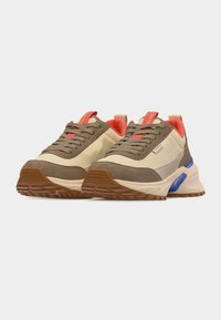 Ζευγάρι μπεζ και καφέ αθλητικά παπούτσια με κόκκινη εσωτερική επένδυση, καφέ κορδόνια και μπλε λεπτομέρειες σε παχιές λευκές σόλες, τοποθετημένα πλάγια δίπλα-δίπλα σε λευκό φόντο.