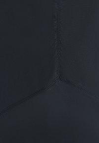 Tessuto per costume da bagno nero con una texture liscia, caratterizzato da cuciture flatlock e un design angolato e triangolare al centro.