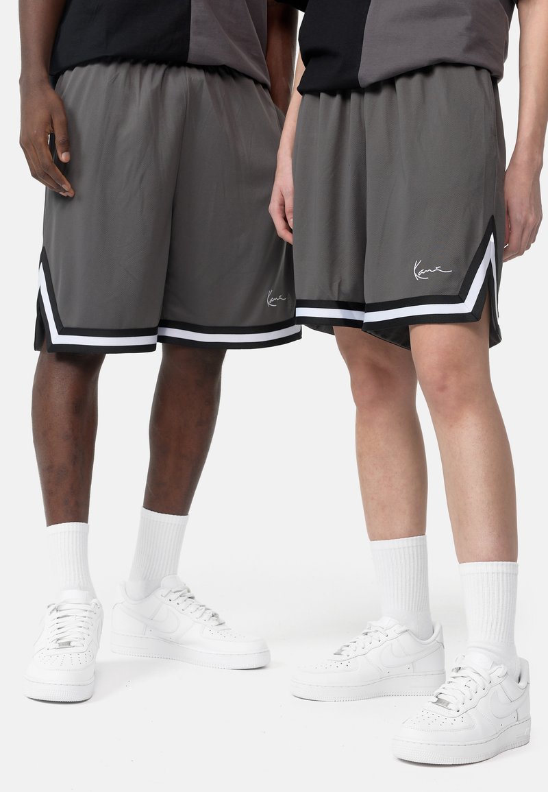 Shorts atletici grigi con finitura testurizzata, dotati di un orlo bianco e nero, fessure laterali e un piccolo logo sulla parte inferiore della gamba sinistra.