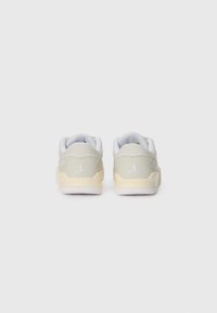 Grå og hvite sneakers med en glatt tekstur, med en beige såle, hvite detaljer og en logo på hælen. Rundet form og lav design.