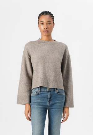 Grey cropped sweater with wide sleeves, ribbed hem, textured knit pattern, paired with blue skinny jeans. Neutral tones and soft fabric.