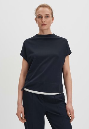 Top blu navy a maniche corte con un collo alto e un accento bianco all'orlo. Tessuto morbido con una vestibilità comoda, abbinato a pantaloni blu navy coordinati.