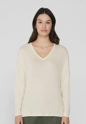 Top a maniche lunghe color crema con scollatura a V realizzato in un tessuto morbido. Presenta una vestibilità comoda e spalle scese per il massimo comfort. Senza pattern visibili.