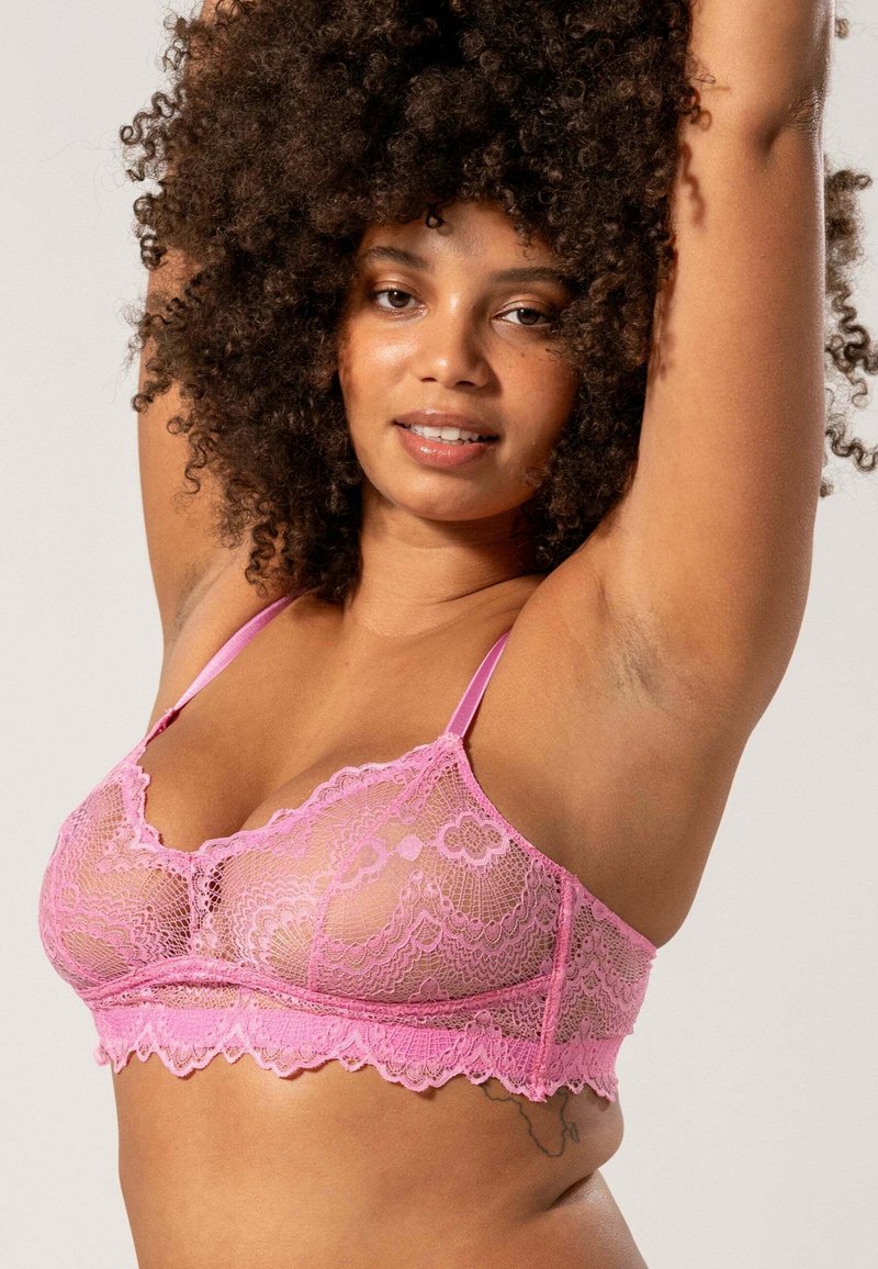 Roze kanten bralette met ingewikkelde bloempatronen, golvende randen en verstelbare schouderbandjes; doorschijnende stof met een zachte textuur.
