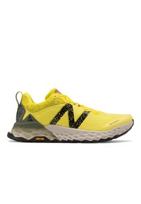 Zapatilla deportiva amarilla con parte superior de malla, acentos negros y suela de goma. Presenta una entresuela acolchada y la marca Vibram cerca del talón.