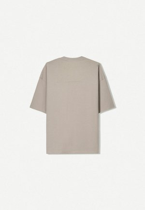 Tricou cu mânecă scurtă din bumbac bej deschis, având guler tip croșetat și un design minimalist, fără modele sau accente vizibile.