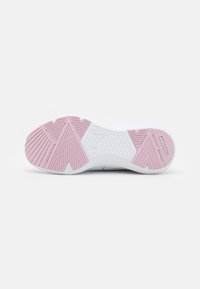 Suela de zapato con una base de goma blanca y acentos en rosa, presentando patrones texturizados y ranuras para mejorar el agarre. Incluye un detalle de marca.