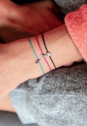 Trois bracelets en cordon ajustables : un bleu, un rose et un noir, chacun doté d'un petit charm en argent avec des détails délicats.