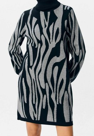 Schwarzes und graues Langarm-Stehkragenkleid mit abstraktem gewelltem Streifenmuster, getragen von einer Person mit hinter dem Rücken verschränkten Händen.