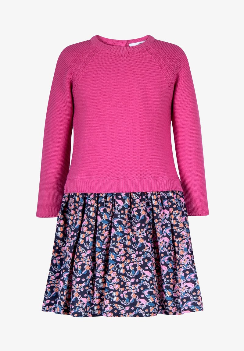 Różowy dzianinowy top z długim rękawem, zestawiony z granatową spódnicą w kwiatowy wzór z wielokolorowymi kwiatami i plisowanym wykończeniem.