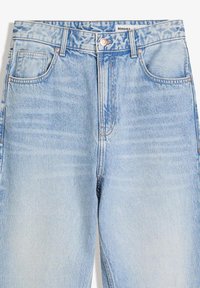 Lichtblauwe denim jeans met voorkruiszakken, riemlussen en een zichtbare metalen knop, met een "BERSHKA" label op de tailleband.