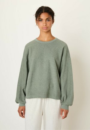 Light green, oversized pullover sweatshirt in soft, textured fabric. Features a round neckline and balloon sleeves. Paired with light-colored pants.