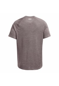 Camiseta deportiva de manga corta en gris con un diseño texturizado. Presenta mangas raglán y un logo en la parte superior de la espalda. Acabado de tela suave.