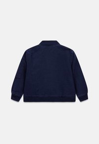 Veste bomber légère bleu marine avec col et poignets côtelés, présentant une texture lisse et une coupe décontractée, sans logos ni motifs visibles.
