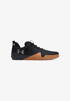 Zapatilla deportiva de perfil bajo negra y marrón con suela texturizada, diseño con cordones y logo de Under Armour en el lateral.