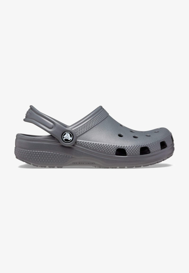 Sabot gris unique à enfiler avec des trous de ventilation, une semelle texturée et une bride de talon réglable avec un bouton logo sur fond blanc.