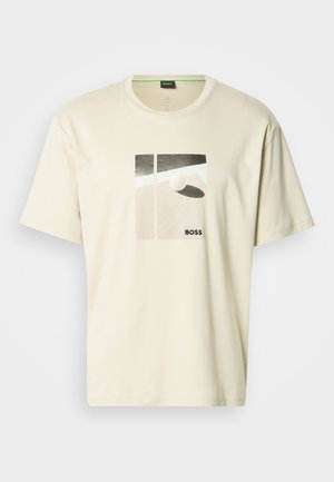 Kremfarget t-skjorte laget av bomull, med et grafisk design med geometriske former og ordet "BOSS" trykt i svart. Kortermet.