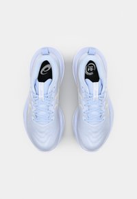 Baskets de sport bleu clair avec une texture lisse, dotées de lacets, d'un logo sur la languette et d'accents réfléchissants sur les côtés.