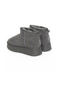 Botas de tobillo de ante gris con un suave forro de piel, parte superior texturizada y suelas de goma planas; cuentan con lengüetas en la parte posterior para facilitar su uso.