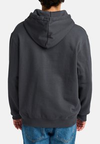 Dark grey hoodie made of soft, textured fabric. Features a large hood, ribbed cuffs, and hem. The back is simple, with no visible logos.