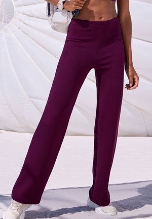 Purple ribbed wide-leg trousers with a high waist, featuring a textured fabric and a flattering fit, paired with white sneakers.