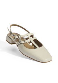 Beige slingback shoe with a square toe, leather upper, and two adjustable straps featuring silver-tone buckles. Low block heel.