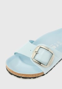 Ljusblå sandal med en slät syntetisk ovandel, silverfärgad spänne och en korksula med en svart gummisula.