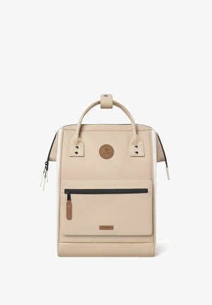 Sac à dos beige en tissu texturé, avec une poignée supérieure, une poche zippée à l'avant et des accents en cuir. Détail en logo circulaire de marque inclus.
