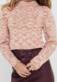 Pull en tricot avec un motif moucheté rose et beige, doté d'un col haut et de manches bouffantes. Assorti à une jupe bordeaux taille haute.