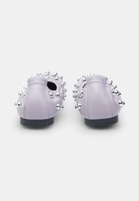 Zapatos slip-on de cuero lavanda con tachuelas plateadas elevadas, punta redondeada, tacón bajo y textura suave.