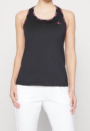 Femme portant un top de sport noir sans manches avec une bordure rose "ONLY PLAY" et un pantalon blanc, debout les mains détendues le long du corps.